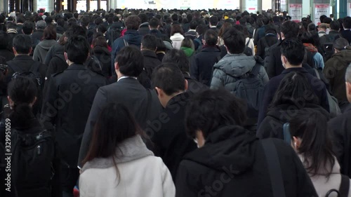 SHINAGAWA, TOKYO, JAPAN - MARCH 2020 : Crowd of people walking down the street in busy morning rush hour. Many commuters going to work. Japanese business, job and lifestyle concept. Slow motion shot. photo