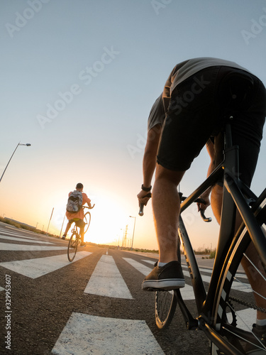 Fototapeta Naklejka Na Ścianę i Meble -  Close up young boys ride bicycles through the city of Seville, sunset.