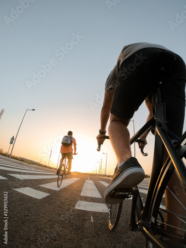 Close up young boys ride bicycles through the city of Seville, sunset.
