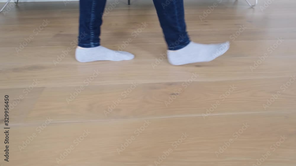 Low angle pan of woman feet in white socks walking on wooden floor in a living room Low angle pan of woman feet in white socks walking on wooden floor in a living room