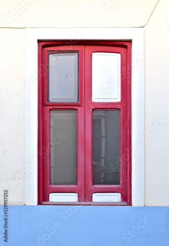 A simple red window in a pale blue wall.