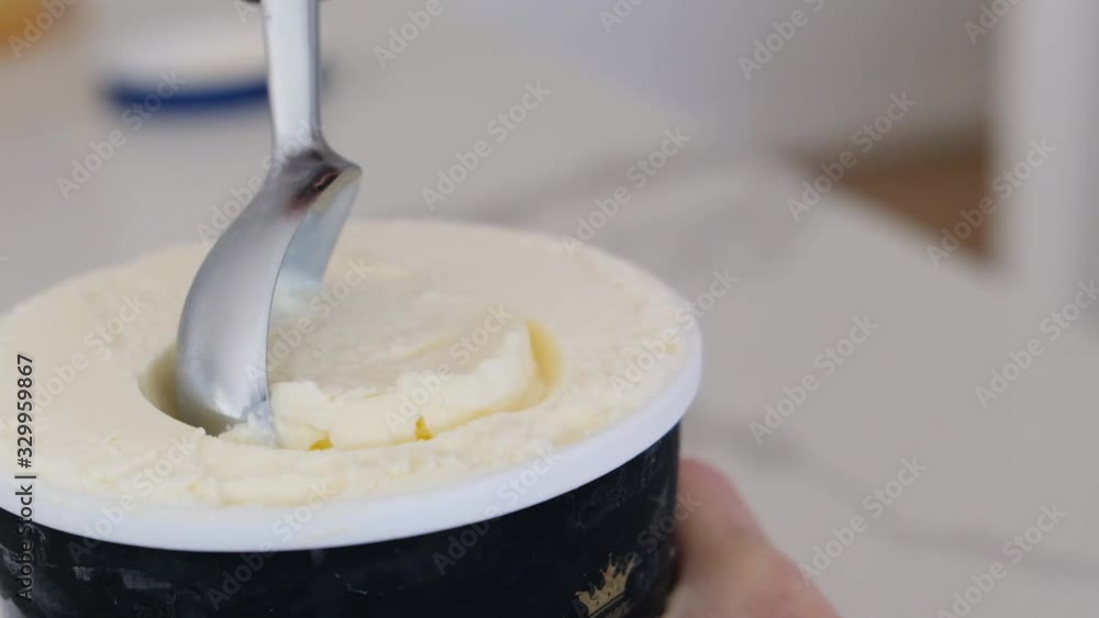 Female hands scooping vanilla ice cream from jar in slow motion with shallow focus Female hands scooping vanilla ice cream from jar in slow motion with shallow focus