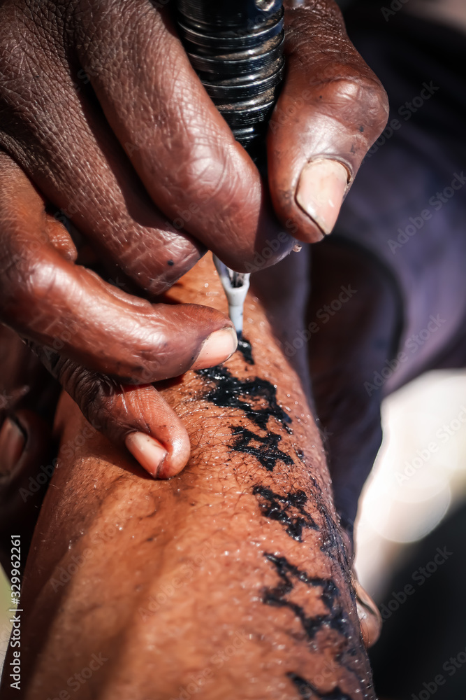 Professional tattoo artist makes a tattoo on a young man’s hand, Professional tattooist working tattooing in India