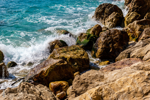 A close-up shot of the Mediterranean Sea turquoise water and powerful waves beating against the rocks on the coast © k.dei