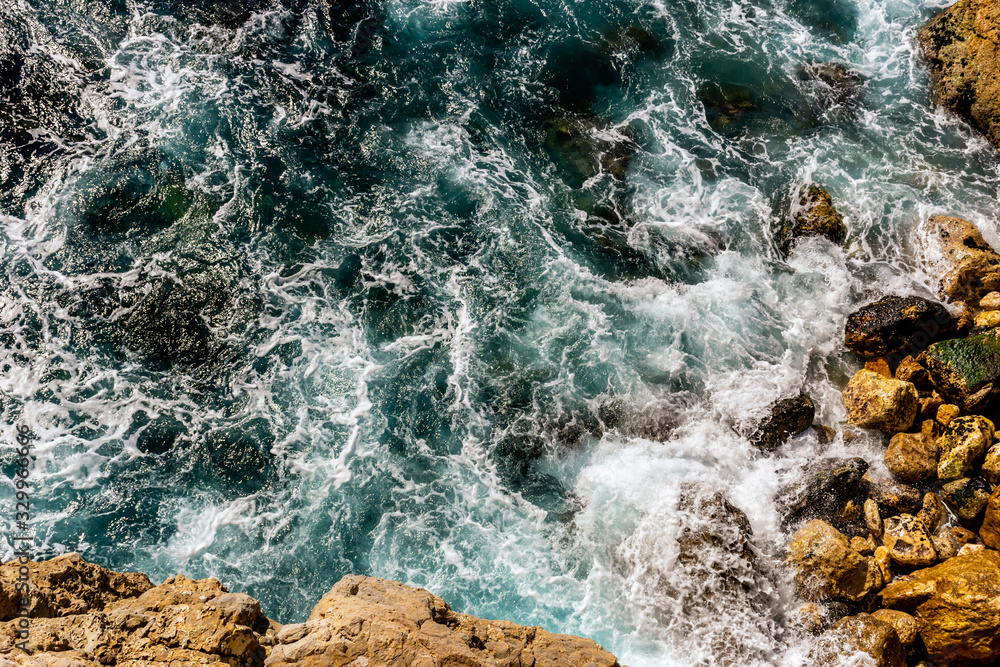 Obraz premium A close-up shot of the Mediterranean Sea turquoise water and powerful waves beating against the rocks on the coast