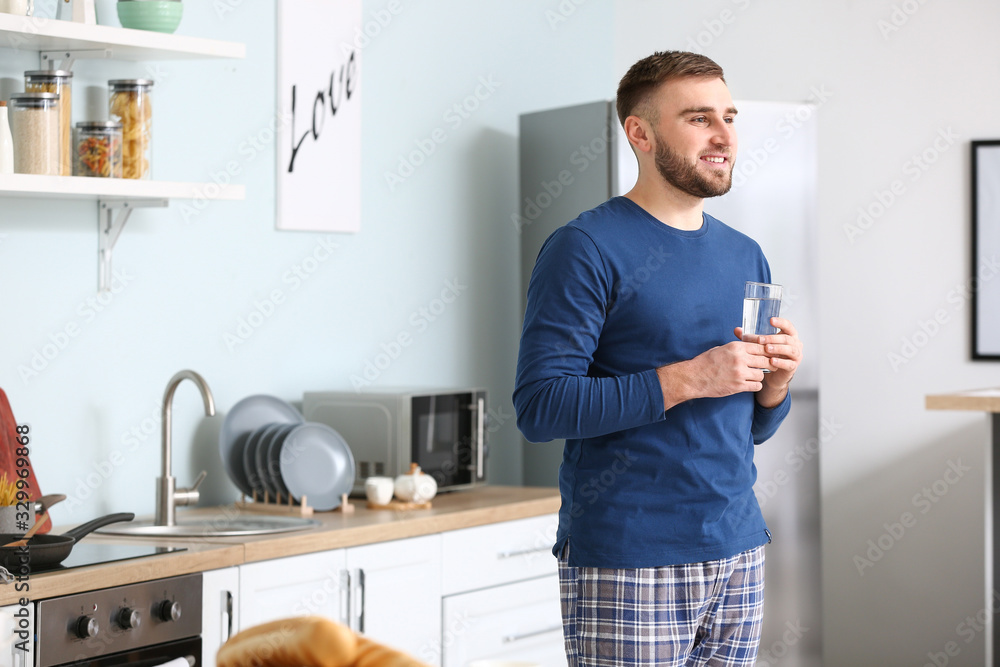 Young man drinking water in kitchen Young man drinking water in kitchen