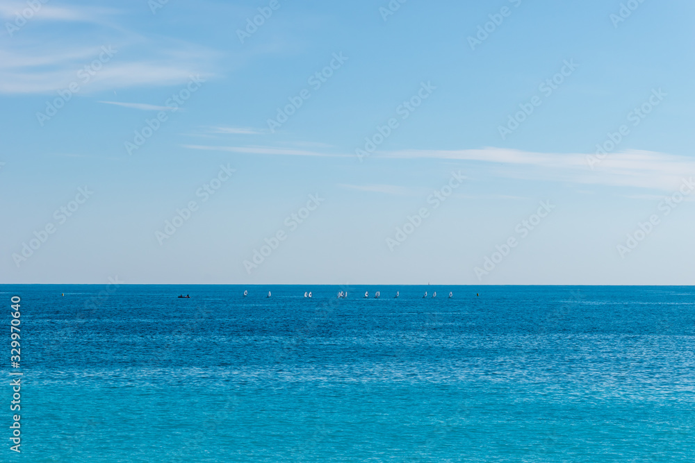 The panoramic view of the turquoise water of the Mediterranean Sea and the white boats in the distance on the horizon on a sunny day (Provence Côte d'Azur, France)