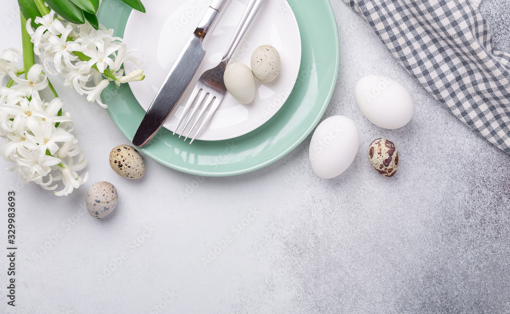 Fototapeta premium Beautiful Easter table setting in Scandinavian style. Green mint plate, eggs and silver cutlery on modern concrete background with hyacinth. Copy space. Top view