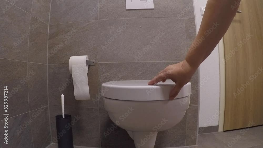 white faience toilet in the toilet room, girl closes the lid with her