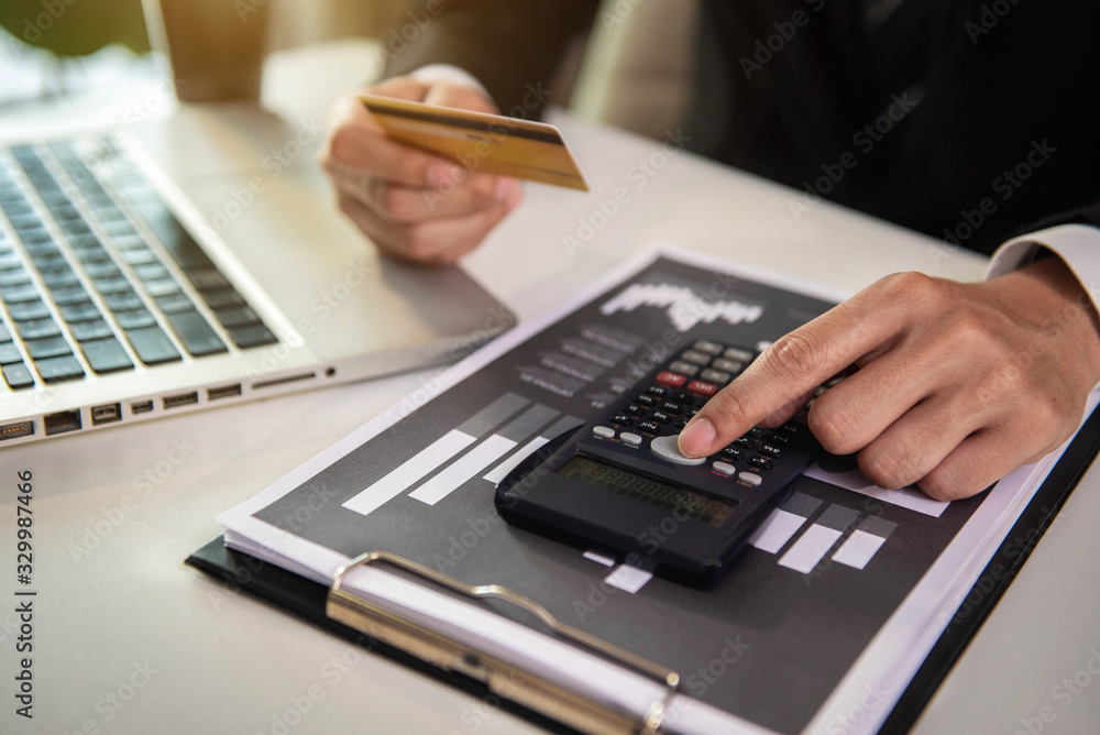Businessman using calculator with credit card for shopping internet online in office. Businessman using calculator with credit card for shopping internet online in office.