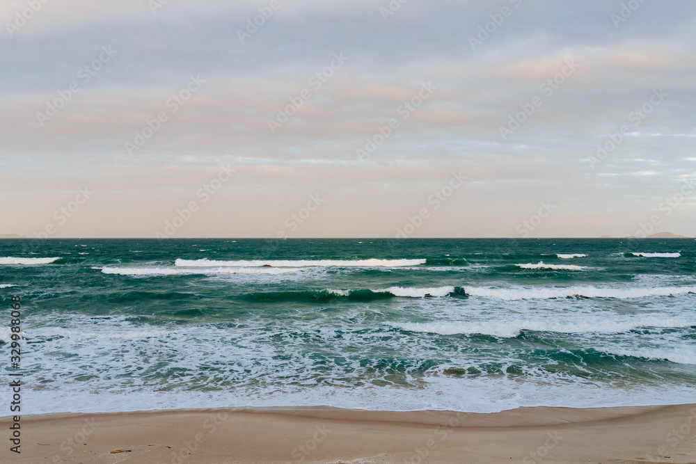 Empty long beach with a beautiful sea view. White foam from a sea wave