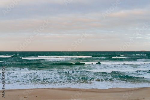Empty long beach with a beautiful sea view. White foam from a sea wave