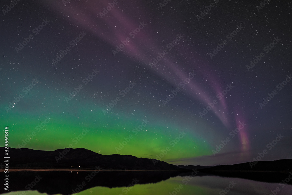 Aurora Borealis Northern Lights seen outside of Whitehorse, Yukon Territory Canada during fall, autumn with bright green band seen along river with reflection in water below. Wallpaper, desktop