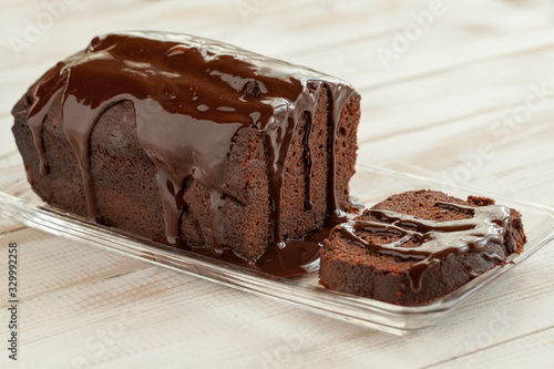 chocolate cake with slice and chocolate topping on a white tabl