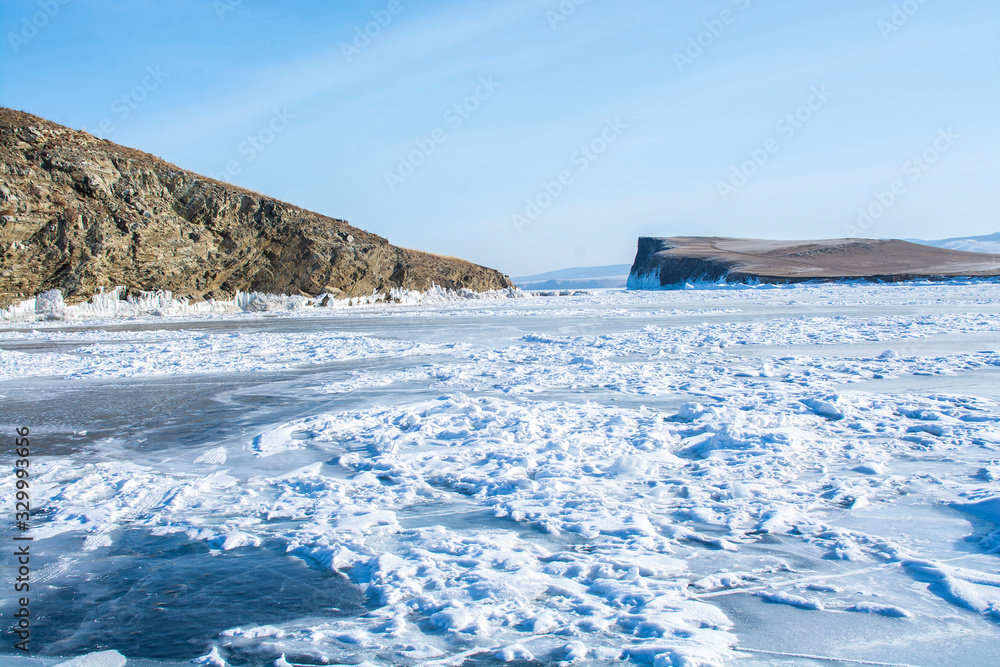Frozen lake with rock islands at background, Baikal Lake in Russia, landscape photography, travel in Siberia, Russia
