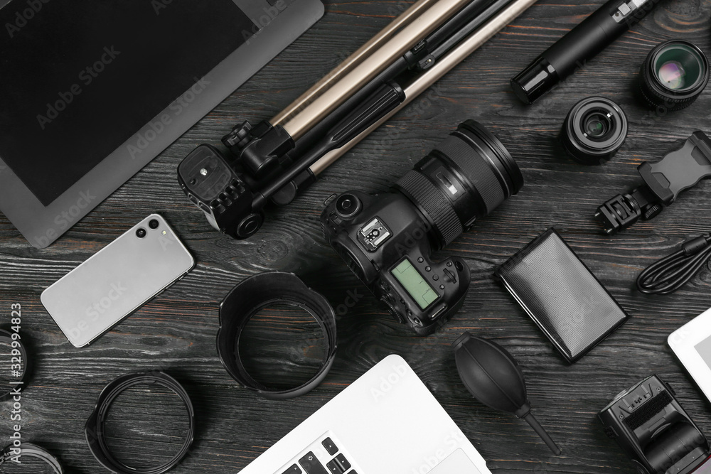 Flat lay composition with camera and video production equipment on black wooden table