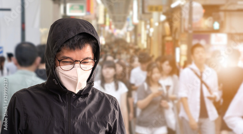 Asian man wearing surgical mask to prevent flu disease Coronavirus with blurred image of people traveling © littlestocker
