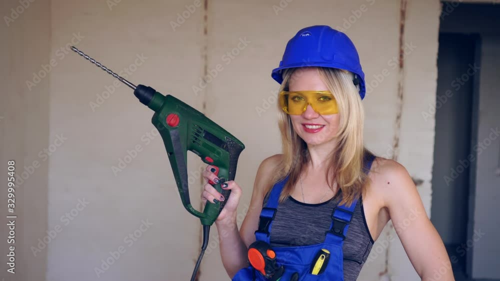 Beautiful woman builder with an electric hammer drill. Beautiful woman builder with an electric hammer drill.