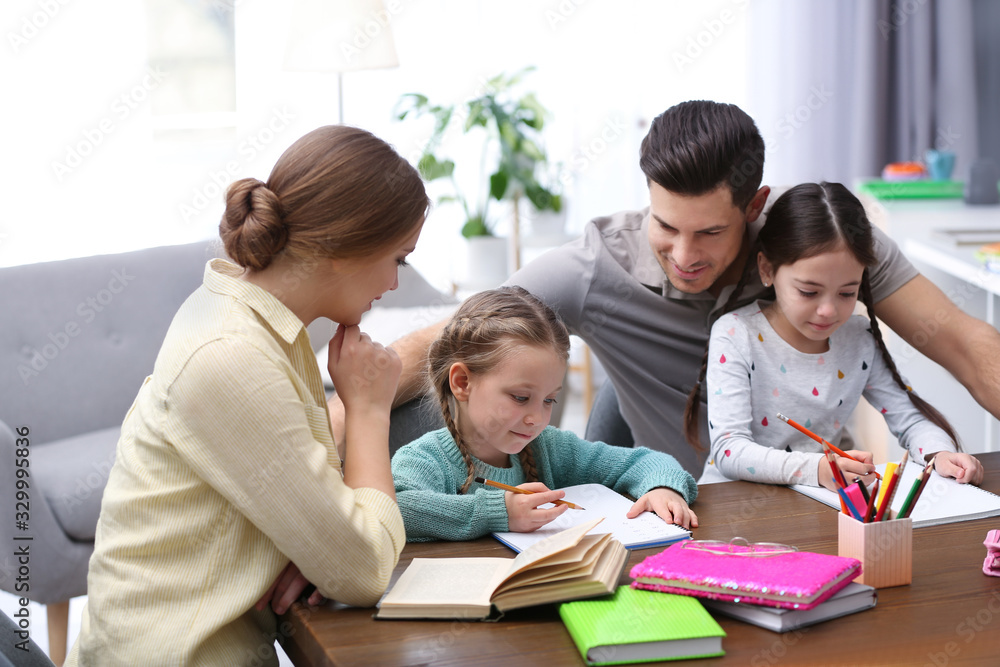 Parents helping their daughters with homework at table indoors Parents helping their daughters with homework at table indoors