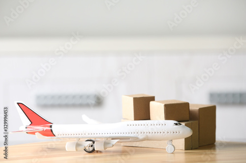 Toy plane and cardboard boxes on table against blurred background, space for text. Courier service
