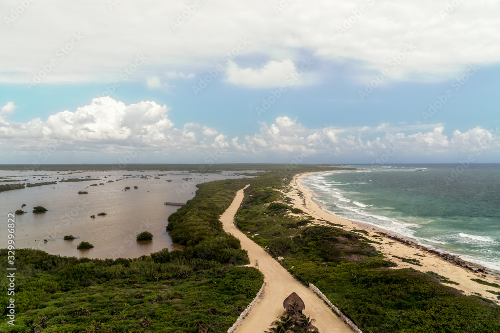 Punta Sur National Park in Cozumel, Mexico. View from the lighthouse. Green jungles and small house with thatched roof. Pink salt lake. Very popular tourist destination. Mother with kids on a tour.