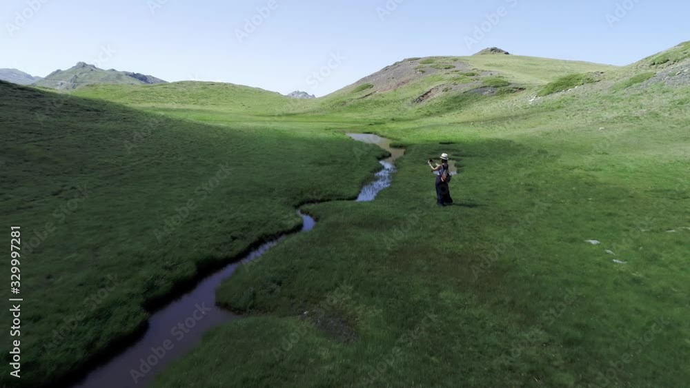 Woman talking photo with her smartphone of alpine lake while landscape is gradually illuminated by sunlight in mountain Grammos, Greece, drone Woman talking photo with her smartphone of alpine lake while landscape is gradually illuminated by sunlight in mountain Grammos, Greece, drone