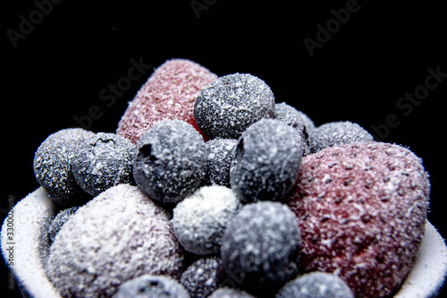 Macro view of frozen berries: strawberry, blueberry on dark background