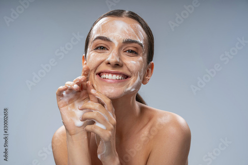 Carta da parati Happy Caucasian woman washing face with white soap