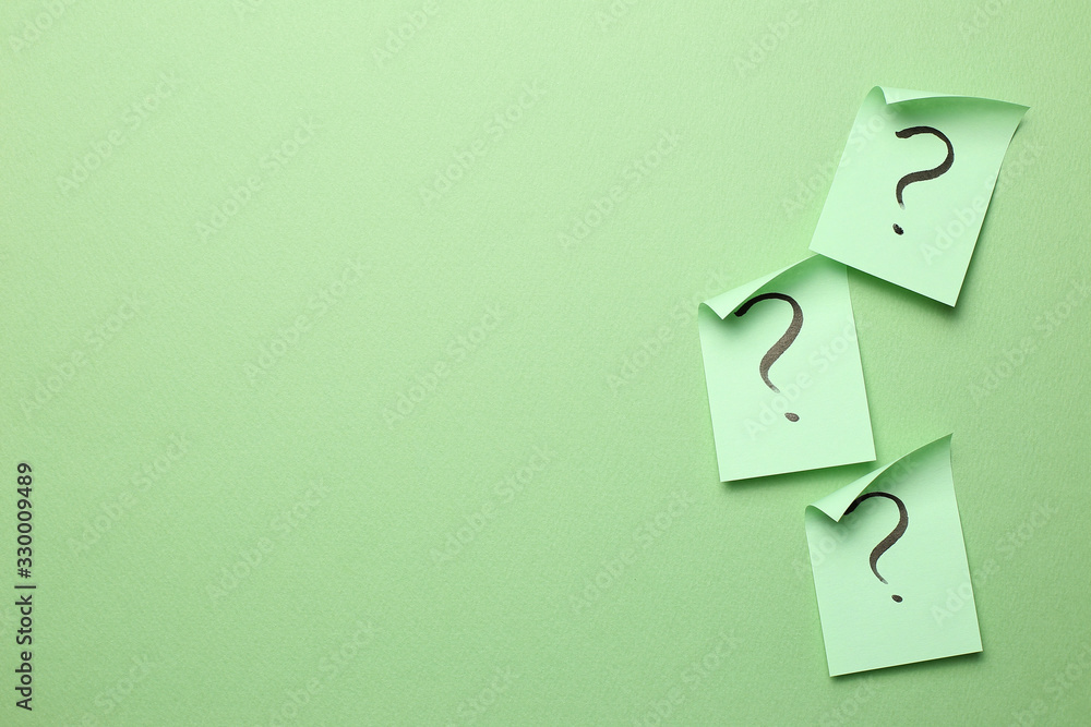 Question mark on memo paper on green background. Solution concept