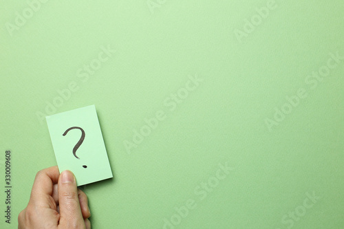 Fotografie Hand holding question mark memo paper on green background