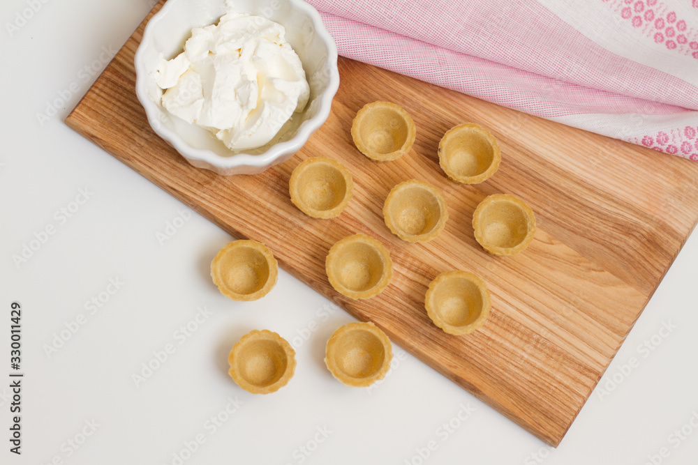 Tartlets with custard or cottage cheese. Empty tartlets or pie on a white table. Food lay flat. The view from the top. The concept of preparing food for the holiday table.