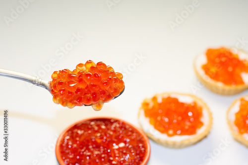 Red caviar in the silver spoon isolated on a white background.