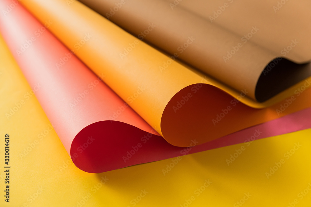 Pink and orange papers rolled together over yellow color paper. Papers for creativity craft and design in school. Pink and orange papers rolled together over yellow color paper. Papers for creativity craft and design in school.