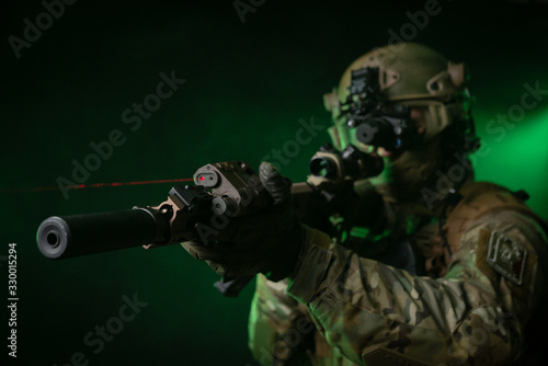 Fotografie a soldier in military clothing with a night vision device and on a dark backgrou