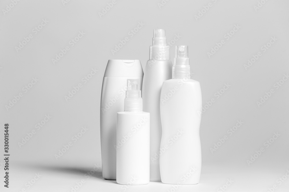 Set of cosmetic products in white and grey containers on light background. Set of cosmetic products in white and grey containers on light background.