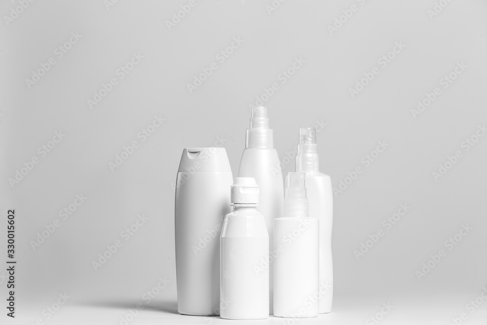 Set of cosmetic products in white and grey containers on light background. Set of cosmetic products in white and grey containers on light background.