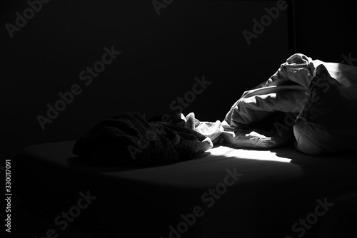 Untidy bed and sleeping cloths on the bed in black and white