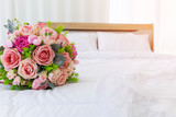 A beautiful bouquet of flowers was laid out on a clean, white bed. Next to the bridal gown were placed together.