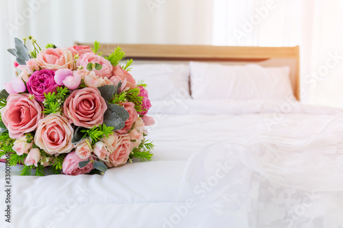 A beautiful bouquet of flowers was laid out on a clean, white bed. Next to the bridal gown were placed together.