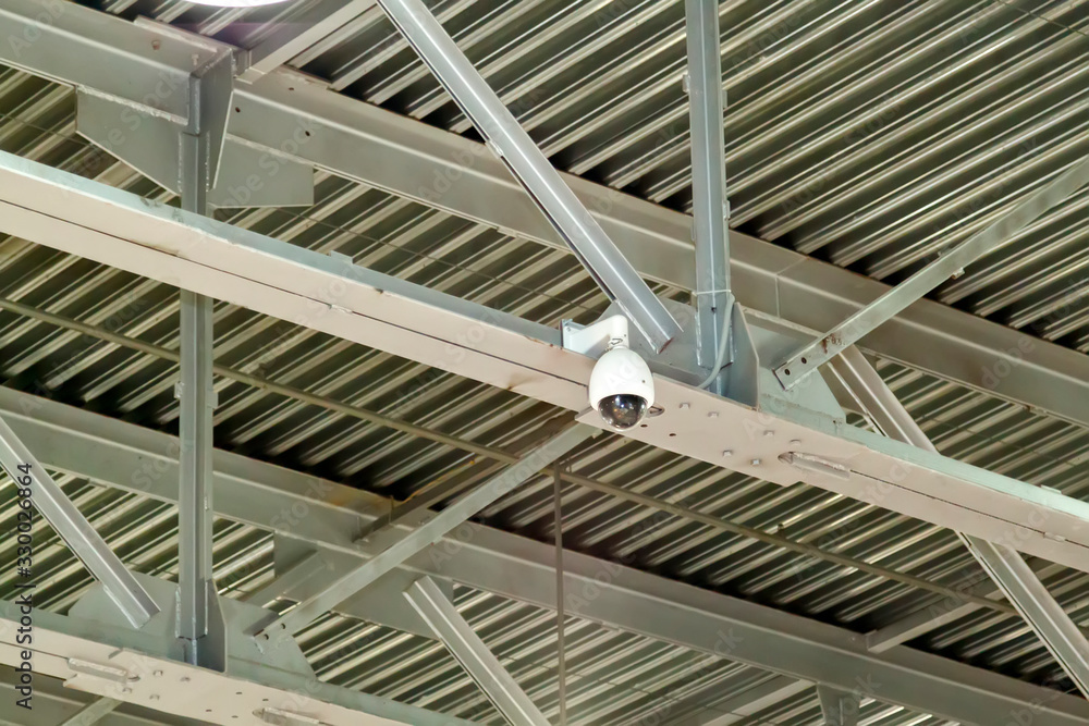 close-up view of a surveillance video camera attached to the joints of metal beams. strong iron construction made of channels that holds the roof close-up view of a surveillance video camera attached to the joints of metal beams. strong iron construction made of channels that holds the roof