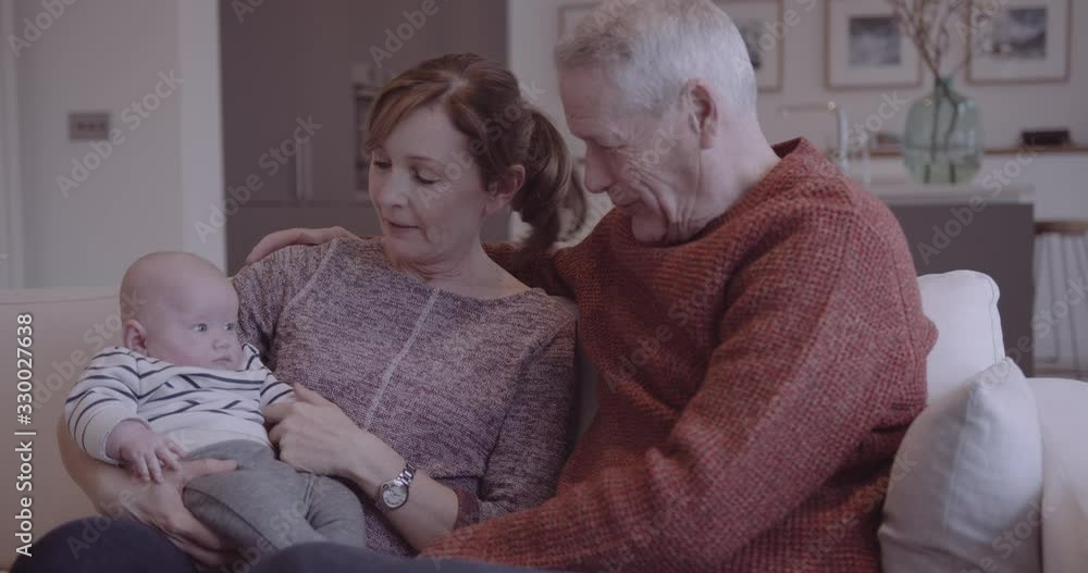 Senior couple embracing grandchild on sofa at home, multi generation togetherness Senior couple embracing grandchild on sofa at home, multi generation togetherness