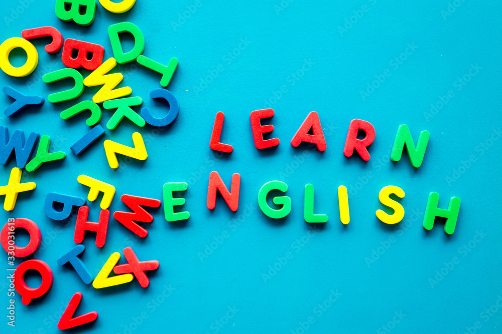 Learn English text near letters on blue background top-down Learn English text near letters on blue background top-down