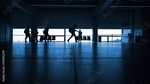 Silhouette of group of students walking through airport terminal with bags