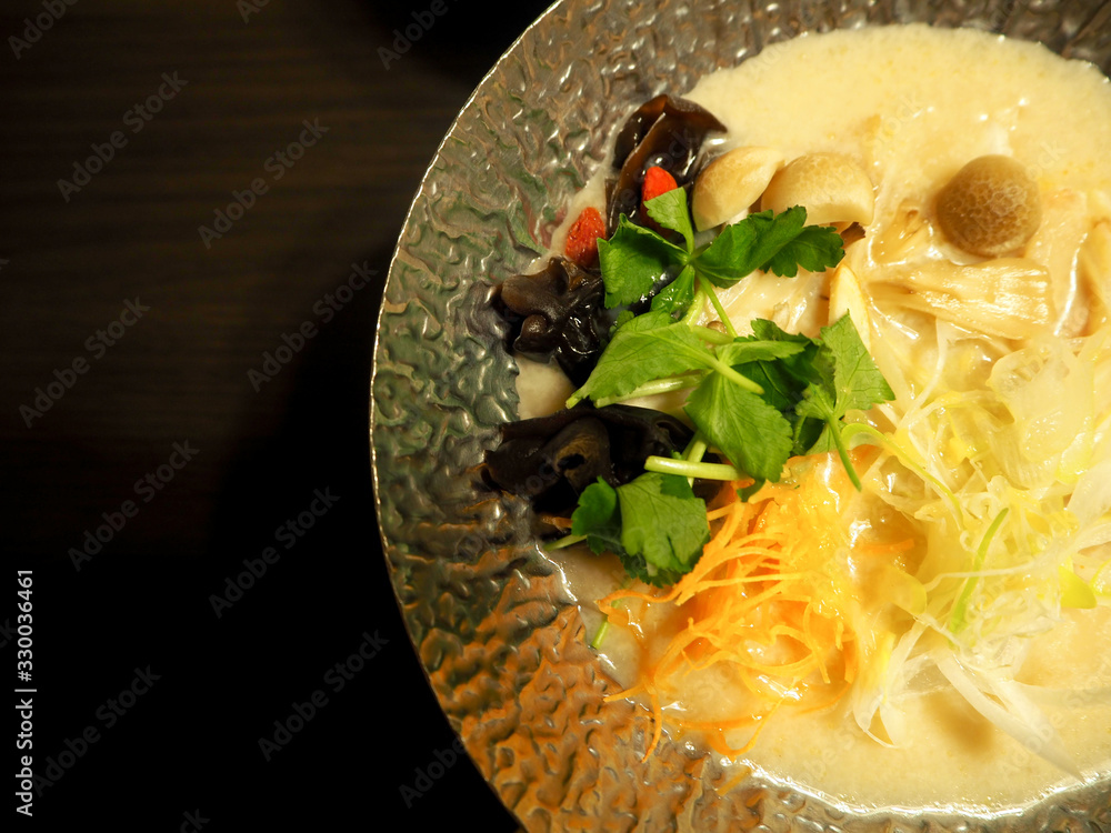 Hot Pot Tonkotsu Soup in silver bowl with coriander leaves.japanese