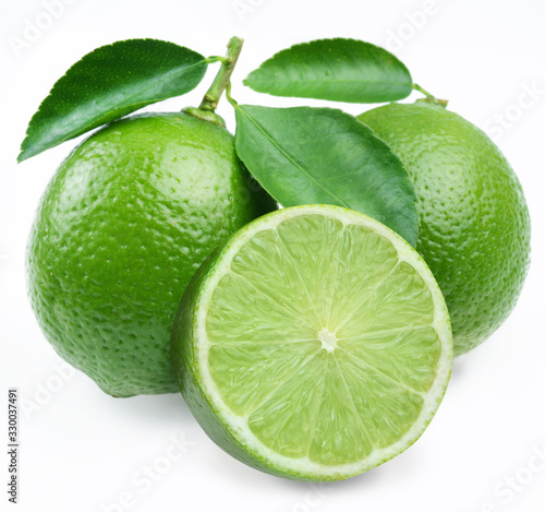 Lime citrus fruit with a slice of lime and leaves isolated on a white background.