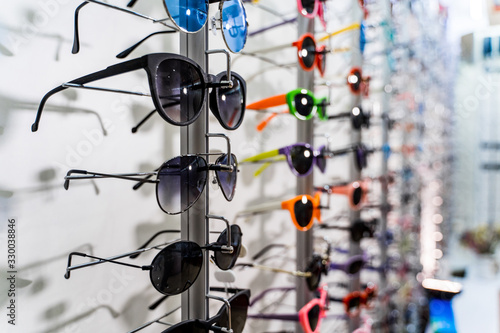 Row of luxury eyeglasses at an opticians store. Sunglasses on the stand.