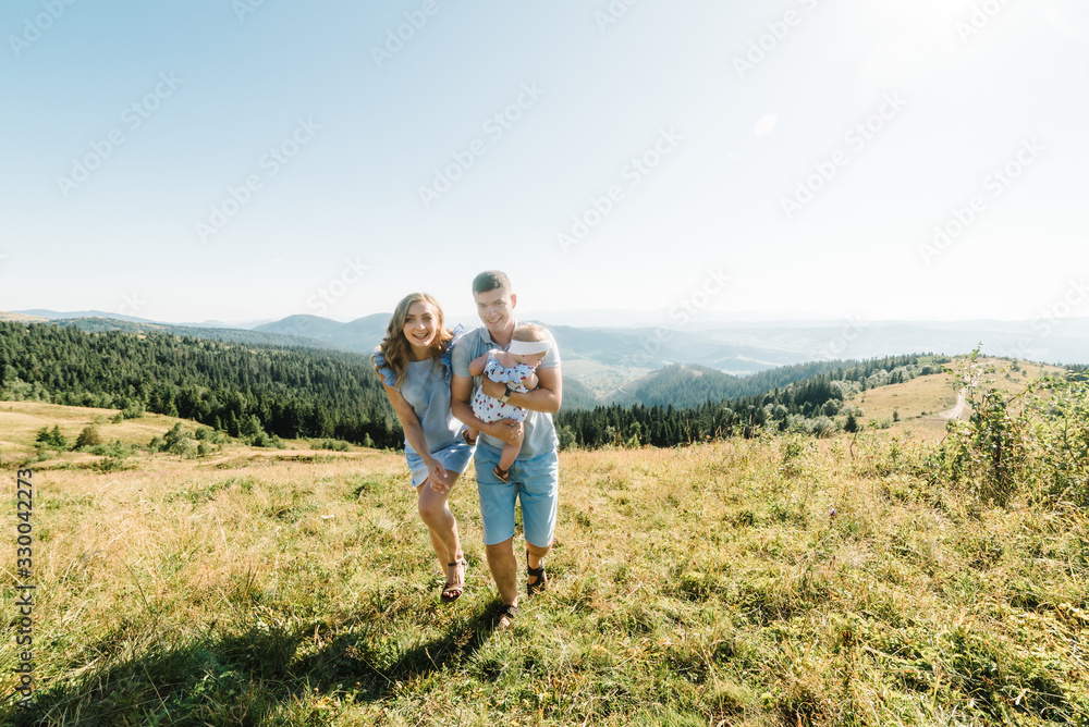 Mom, dad hugging daughter in the mountains enjoy and look at nature. Young family spending time together on vacation, outdoors. The concept of family summer holiday. Mother's, father's, baby's day.