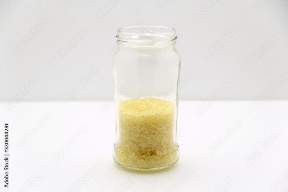 Glass jar with rice on a white background, side view. Glass jar with rice on a white background, side view.
