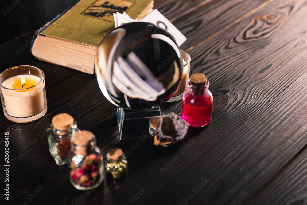 Selective focus of crystal ball with book and occult objects on wooden background Selective focus of crystal ball with book and occult objects on wooden background