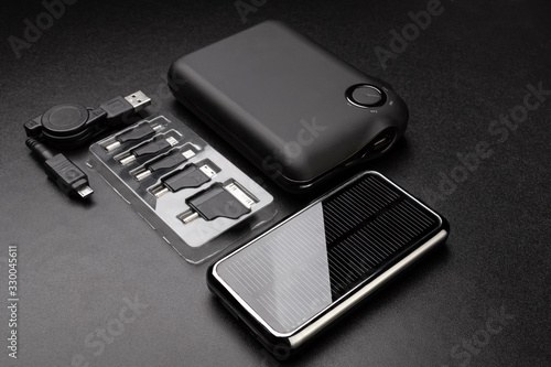 Powerbanks for charging mobile devices and set of recharger heads on black background